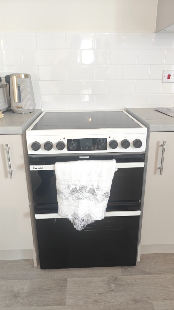 Hisense white double oven electric cooker with ceramic hob installed between cabinets